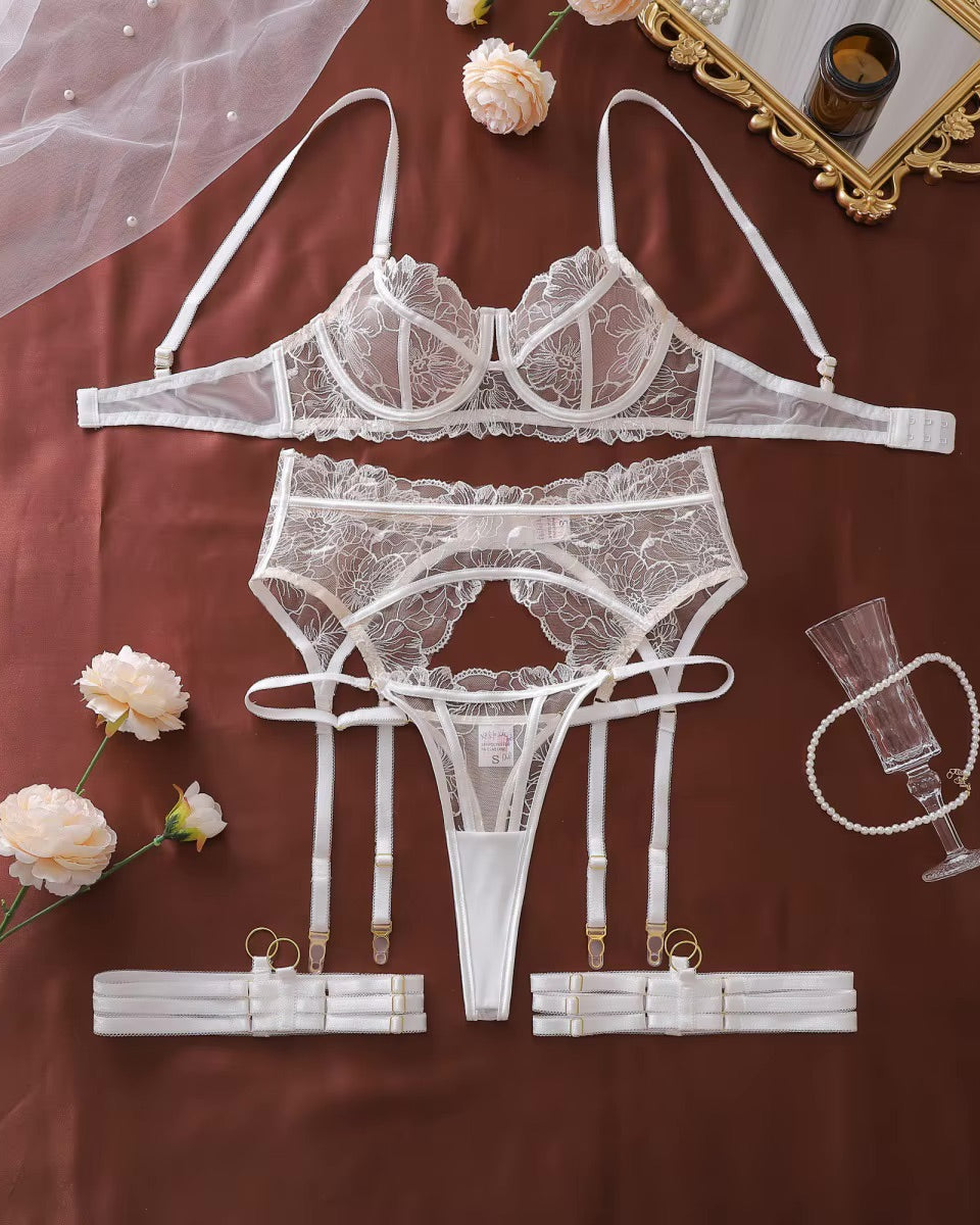 Flat lay of Don't Think Twice white embroidered lingerie set with garter belt and leg straps.