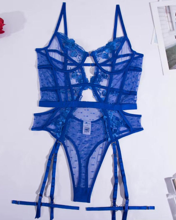 Blue lace lingerie set on a white surface with a red rose and makeup products.
